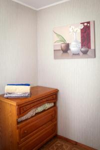 ein Zimmer mit einer hölzernen Kommode mit einer Vase an der Wand in der Unterkunft Pobeda Apartment in Dnipro