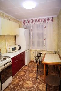 a kitchen with a table and a white refrigerator at Pobeda Apartment in Dnipro