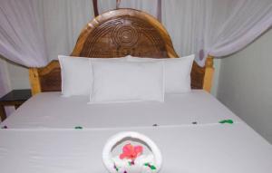 a bed with a wooden head board with a flower on it at Summer Dream Lodge in Paje