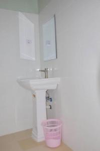 baño con lavabo blanco y cesta rosa en Summer Dream Lodge, en Paje