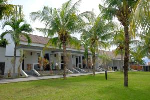 a building with palm trees in front of it at Kuraya Hotel Residence in Bandar Lampung
