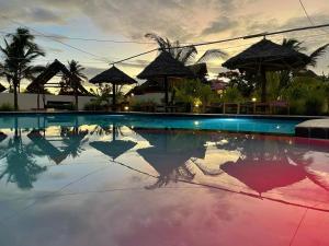 uma piscina num resort com um reflexo na água em Summer Dream Lodge em Paje