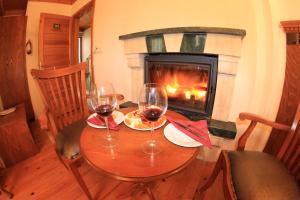 Sazlı的住宿－Assos Kayalar Terrace，壁炉前的桌子和两杯葡萄酒