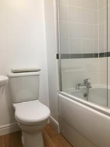 a white bathroom with a toilet and a bath tub at Bullfinch House in Harleston