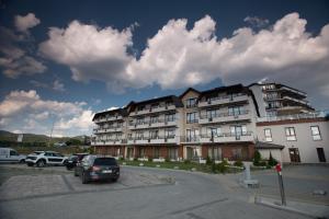 a large building with cars parked in a parking lot at DeltaLux apartmani Milmari Kopaonik in Kopaonik