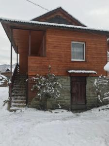 a wooden house with snow on the ground at Міні Котедж in Verkhovyna