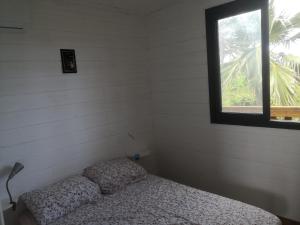 um pequeno quarto com uma cama e uma janela em Ti Kaz en l'R em Saint-Leu
