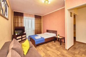 トムスクにあるКвартиры на Карла Ильмераのベッド1台とソファが備わる小さな客室です。
