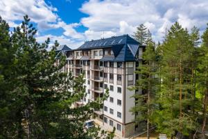 an apartment building with a blue roof at Zlatna zona 59 (Titova vila) in Zlatibor