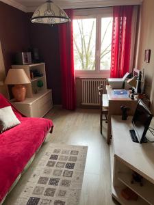 a bedroom with a red bed and a desk and a window at LE CHOUKI in Annecy