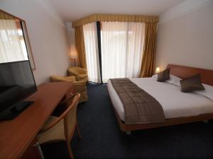 a hotel room with a bed and a desk and a television at Hotel San Rocco in Muggia