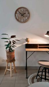 une horloge sur le mur au-dessus d’un piano et d’une plante en pot dans l'établissement Gîte Saint Martin, à Carvin