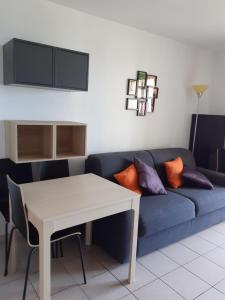 a living room with a blue couch and a table at Studio cabine Thalacap Vue mer in Banyuls-sur-Mer