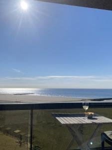 - un verre de vin assis sur une table sur la plage dans l'établissement Prachtig Zeezicht Westcorner, à Middelkerke