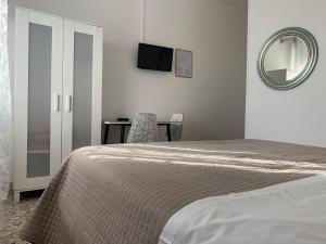una camera da letto con un letto, uno specchio e una sedia di Albergo Moderno a Modena