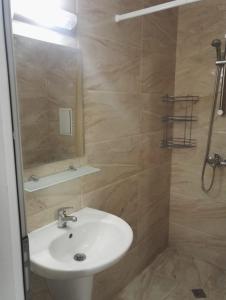 y baño con lavabo y ducha con espejo. en Apartments Sarafovo en Burgas