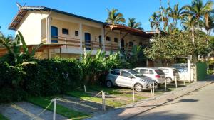 a house with cars parked in front of it at Pousada Canoeiro in Ubatuba