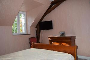 Dormitorio con cama, escritorio y TV en La ferme des Cailloux, en Sassay