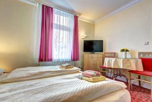um quarto de hotel com duas camas e uma televisão em Pension Mittag em Heringsdorf