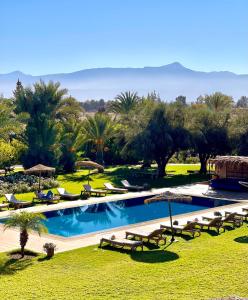 a swimming pool with chairs and umbrellas in a resort at Marrakech Retreat By La Siredrah in Marrakech