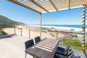 a table and chairs on a balcony with a view of the beach at Picnic Rock Seaside Accommodation in Keurboomstrand
