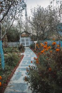 a path in a garden with a white fence and flowers at Enthralling Escapes Nature Stay and Trek in Manāli