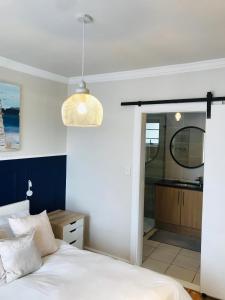 a bedroom with a white bed and a bathroom at 19 Malachite Mews in Knysna