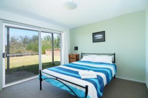 a bedroom with a bed and a large window at Jervis Bay Waterfront in Vincentia