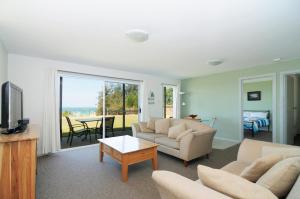 a living room with a couch and a tv and a table at Jervis Bay Waterfront in Vincentia
