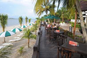 a restaurant on the beach with tables and umbrellas at Flamingo Hotel by the Beach, Penang in George Town