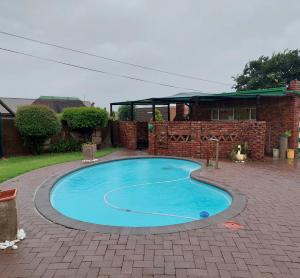 una pequeña piscina azul en un patio de ladrillo en Floret Cottage en Welkom