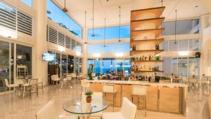 un restaurante con un bar con mesas y sillas blancas en Flamingo Hotel by the Beach, Penang, en George Town