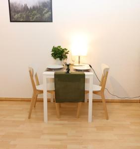 einem weißen Tisch mit zwei Stühlen und einer Lampe darauf in der Unterkunft Kupferberg - helles und gemütliches Appartement in Uninähe in Mainz