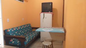 a room with a couch and a tv on top of a refrigerator at Tartaruga Azul in Florianópolis