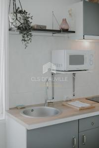 a kitchen counter with a sink and a microwave at La Deauvillaise CLS Deauville in Deauville