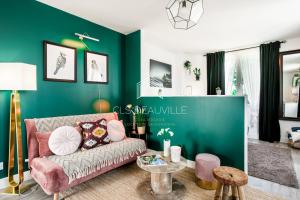 een woonkamer met een roze bank en een groene muur bij La Deauvillaise CLS Deauville in Deauville