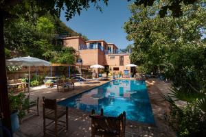 a swimming pool with chairs and umbrellas next to a building at Auberge le Maquis in Aghbalou