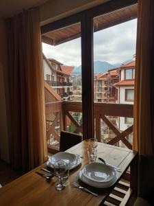 a table with plates and glasses and a large window at Studio in Murphys Lodge in Bansko