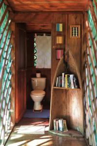 a bathroom with a toilet and a book shelf with books at El Hotelito Perdido in Río Dulce