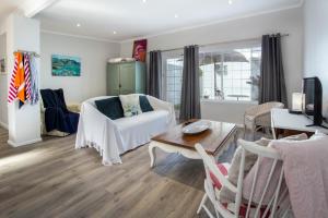 una sala de estar con un sofá y una mesa en Goozi Garden Cottage, en Hermanus