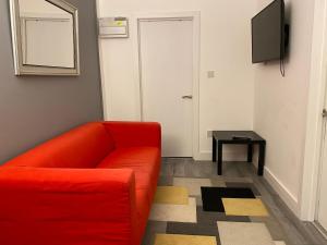 a living room with a red couch and a tv at Cosy 2 Bed Flat 1 in Bridgend in Bridgend