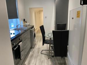 a kitchen with a glass table and black chairs at Cosy 2 Bed Flat 1 in Bridgend in Bridgend