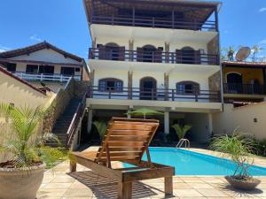 una silla frente a una casa con piscina en Praia Virgem Hostel, en Rio das Ostras