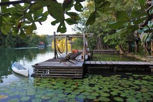 a dock with a boat on a lake with water lilies at El Hotelito Perdido in Río Dulce