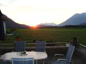 einen Tisch und Stühle auf einer Terrasse mit Blick auf den Sonnenuntergang in der Unterkunft Ferienwohnung Millonigg in Vorderberg