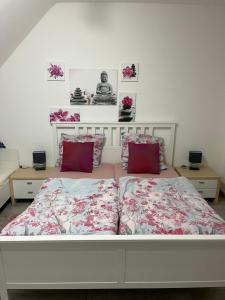 a white bed with two red pillows on it at Sweet Home Appartements in Bottrop