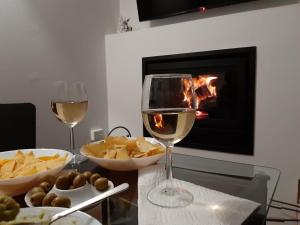 a table with two glasses of wine and chips and a fireplace at Ledro Lake Suites in Ledro