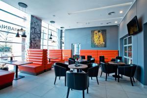 restauracja z pomarańczowymi i czarnymi stołami i krzesłami w obiekcie Hotel Europa w Lubinie