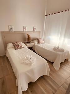 two beds with white sheets in a room at La Pedrera Apart in Villa María