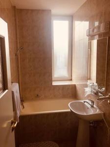 a bathroom with a sink and a bath tub and a window at HOTEL MUNTENIA in Câmpina +69 photos